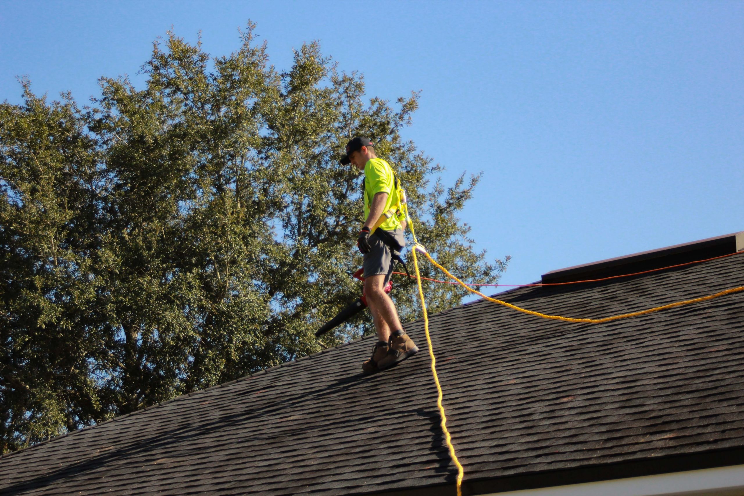 Roofer tied to the roof walking around.