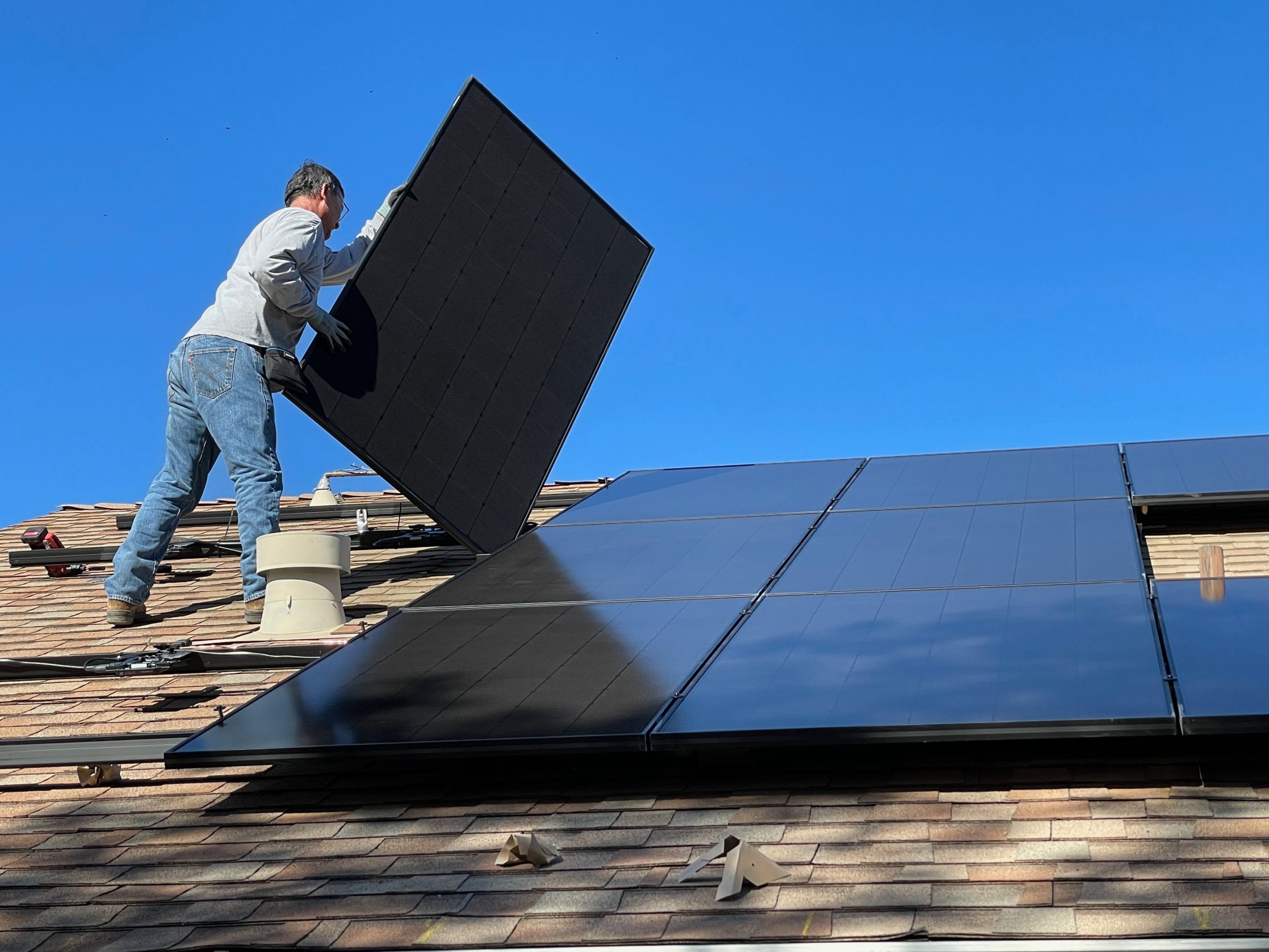 Man putting solar panels onto a roof.