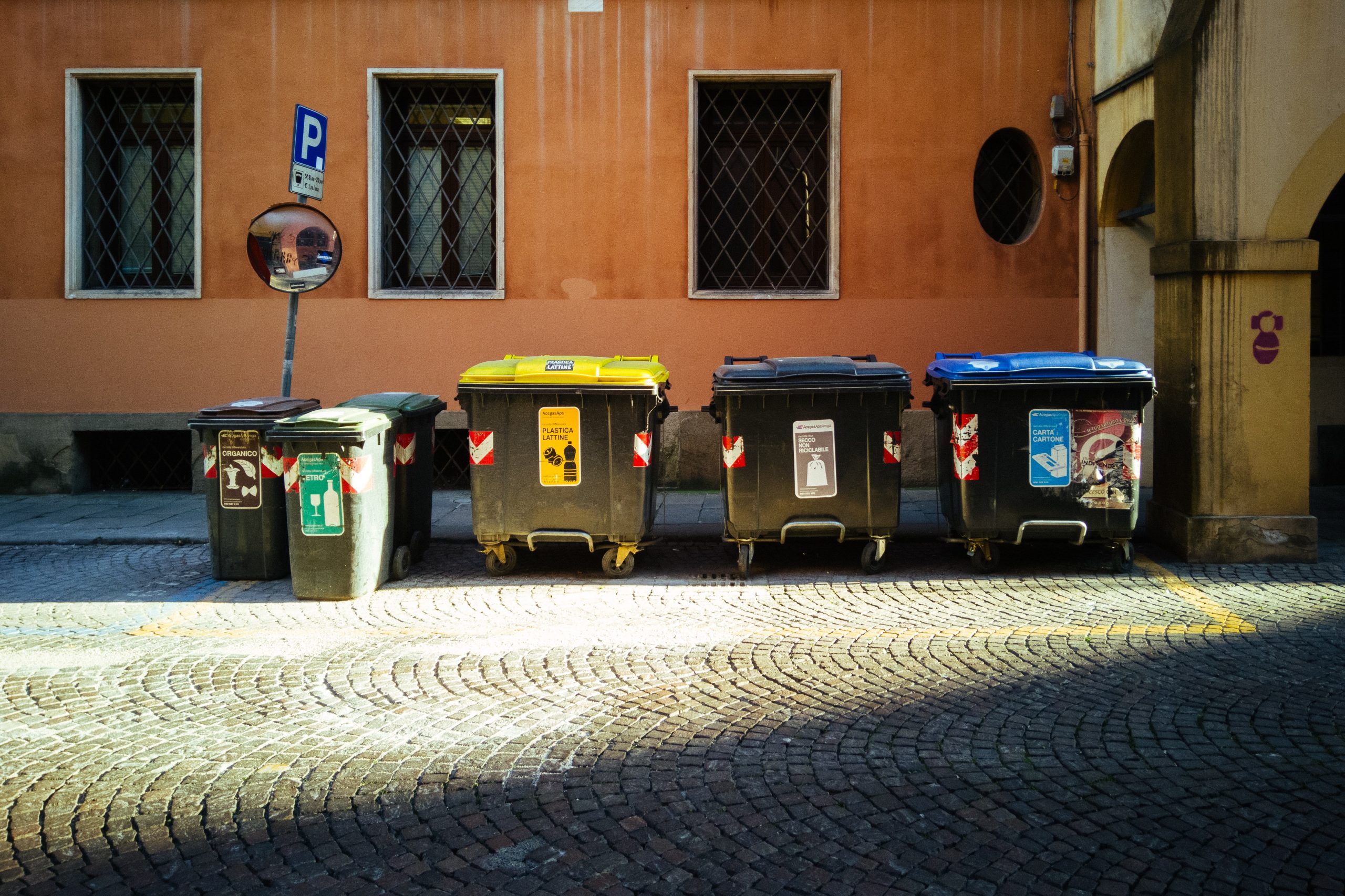 Trash and recycling bins lined up on the side of the building